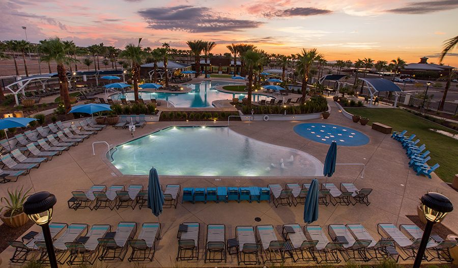 Resort-style pool at the Verrado community in Buckeye, Arizona, featuring palm trees, lounge chairs, and sunset views. As Buckeye continues to lead the nation in homeownership in 2024, Verrado offers luxury amenities like this stunning pool, enhancing the appeal for families and homeowners seeking a vibrant, community-centered lifestyle in Arizona's top-ranked city.