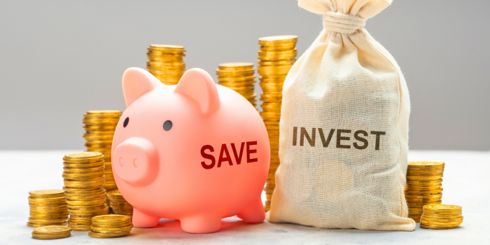 Piggy bank labeled 'Save' next to a money bag labeled 'Invest' surrounded by stacked coins, symbolizing the strategy of saving on mortgage payments through a 3-2-1 buydown and investing those savings to build wealth.