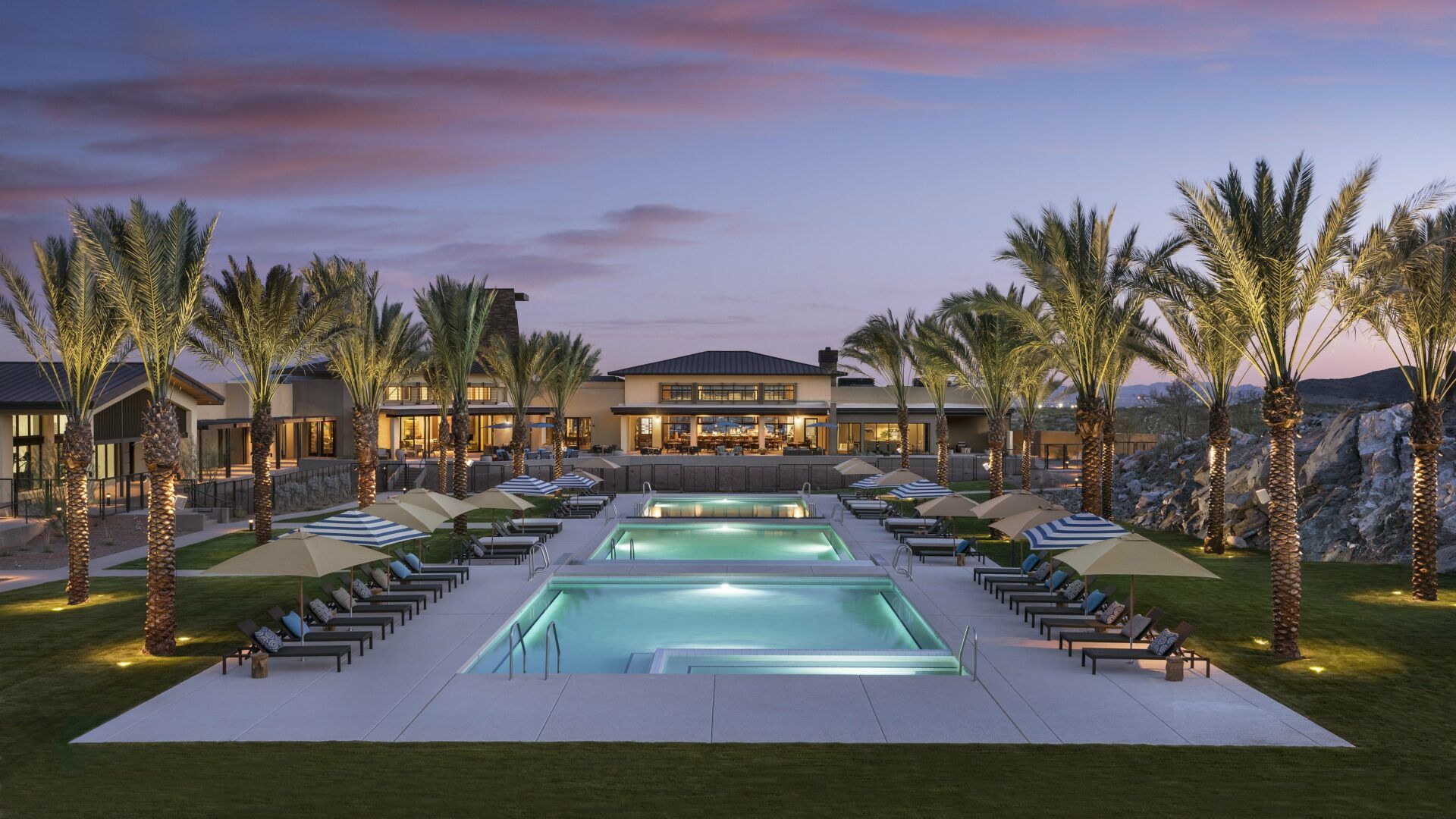 Luxury amenities at a top-rated 55+ active adult community in the Phoenix Metro area, showcasing resort-style pools, palm trees, and a modern clubhouse, epitomizing the vibrant lifestyle available in Arizona's best retirement communities.