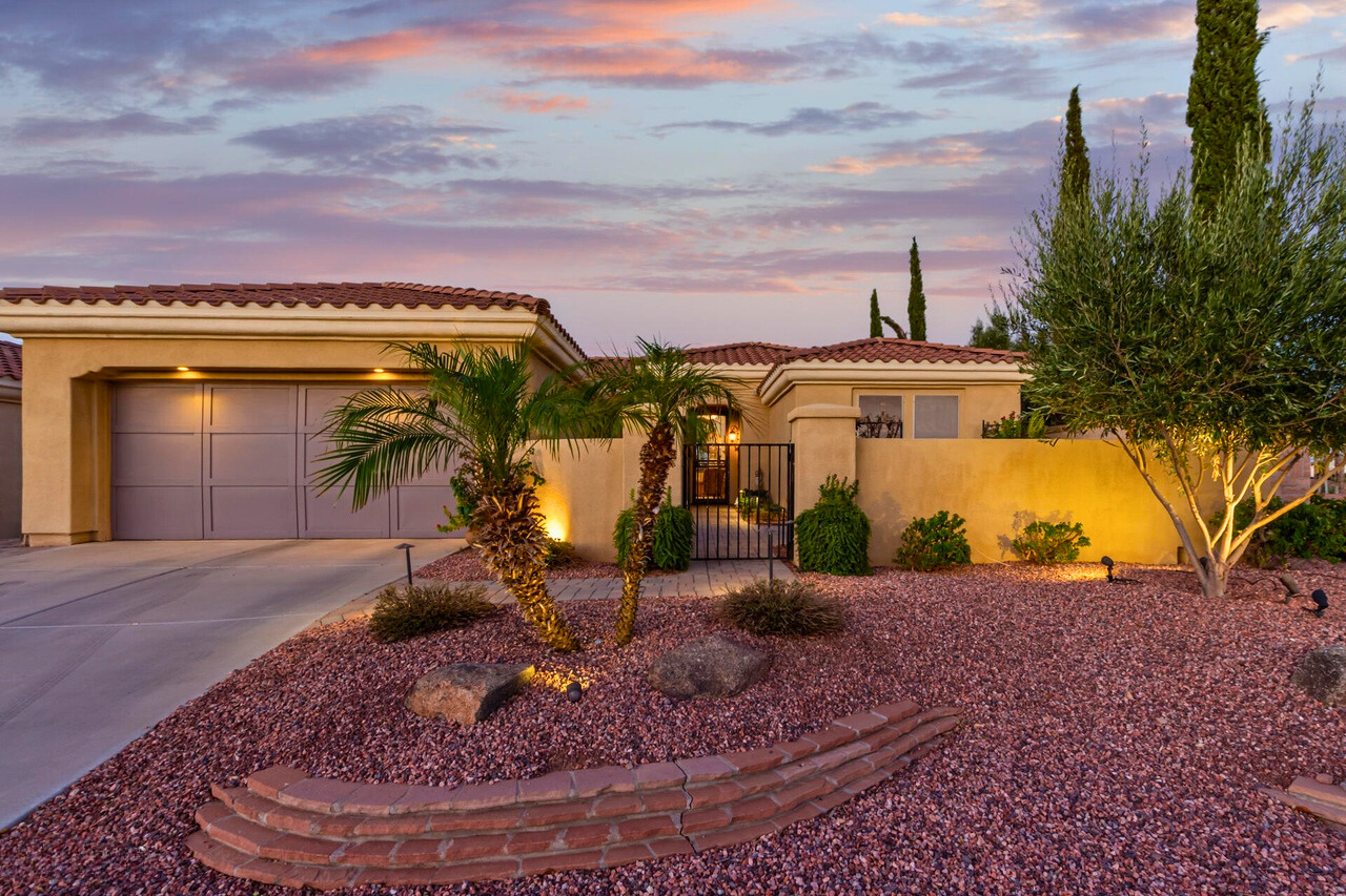 Beautiful single-story home at Corte Bella in Sun City West, AZ, showcasing the Spanish Colonial architectural style with a stucco exterior, red-tiled roof, and desert landscaping, highlighting the variety of elegant home designs available in this 55+ active adult community.