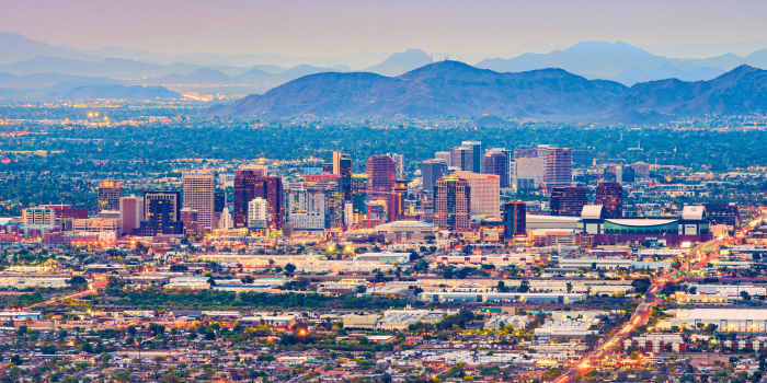 Phoenix, Arizona skyline at sunset with vibrant city lights and picturesque mountain views, showcasing a lifestyle similar to California with warm climates, urban amenities, and proximity to stunning natural landscapes.