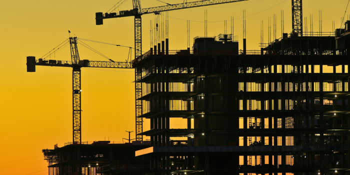 Silhouette of construction cranes and buildings against a vibrant sunset, symbolizing Arizona's rapid growth and booming job market fueled by expanding industries like technology, healthcare, and real estate development.