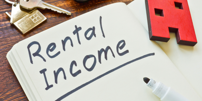 Image featuring a notebook with 'Rental Income' written on it, alongside a marker, keys, and a red house icon, symbolizing strategies to maximize rental income through effective property management, competitive pricing, and tenant retention.