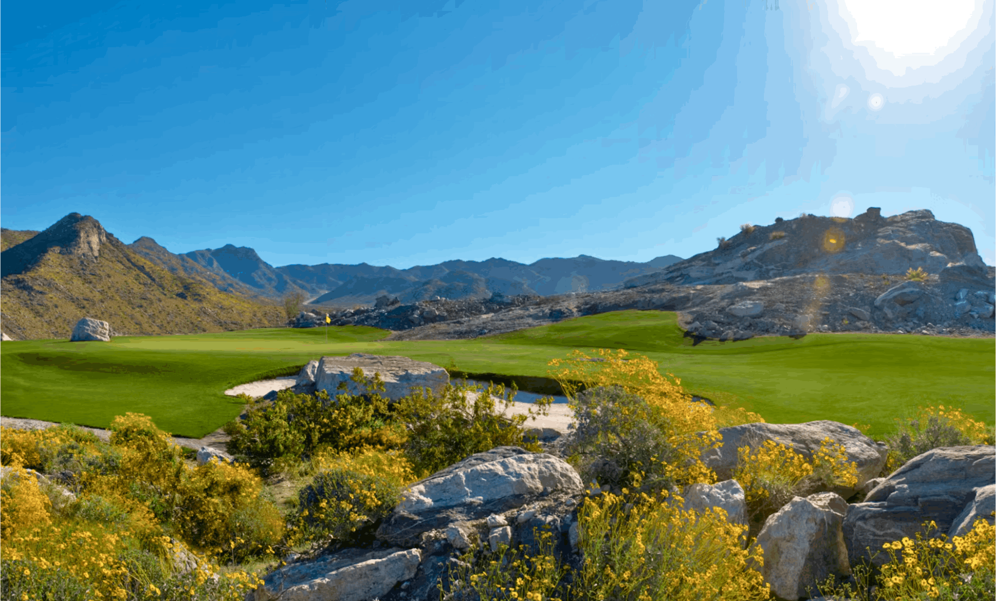 Scenic Arizona desert golf course under clear blue skies with wildflowers and rocky landscape – a perfect snowbird destination for winter warmth and stunning natural beauty.