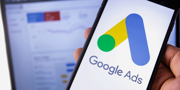 Close-up of a smartphone displaying the Google Ads logo with an ad campaign dashboard in the background, representing advanced marketing strategies like running targeted ad campaigns to increase direct bookings for vacation rentals and short-term rentals.