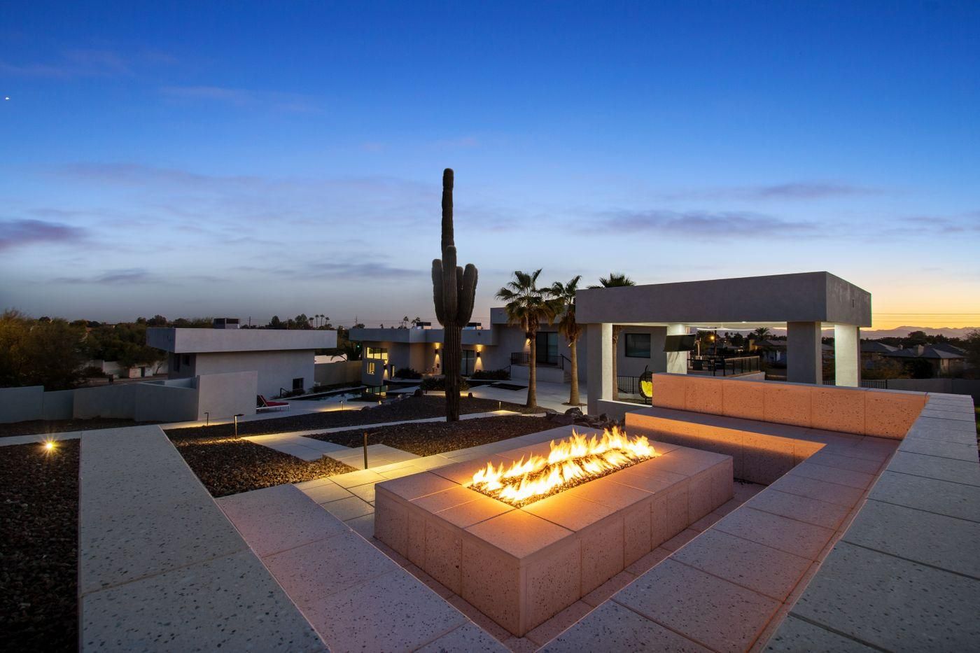 Modern rooftop stargazing deck with a cozy fire pit, cactus centerpiece, and panoramic views at twilight, showcasing standout amenities perfect for attracting astronomy enthusiasts and creating unforgettable vacation rental experiences.