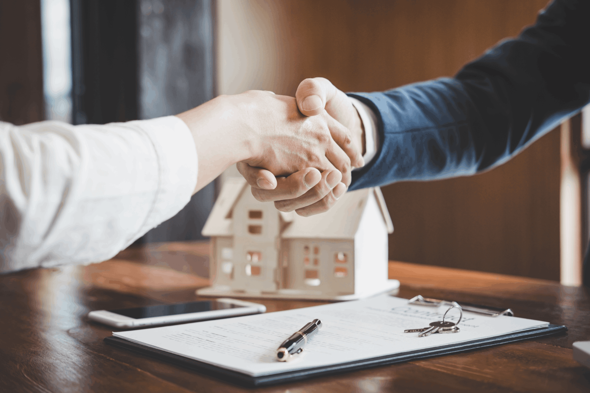 Two hands clasping each other for a hand shake in the middle of the frame.