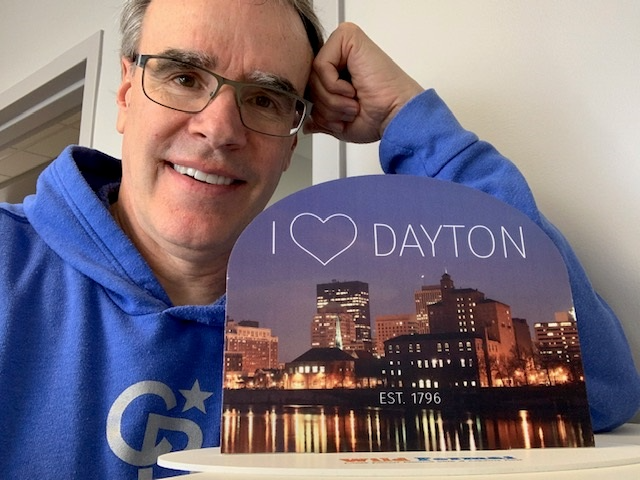 David Campbell leaning over a sign that Reads I "Heart" Dayton.