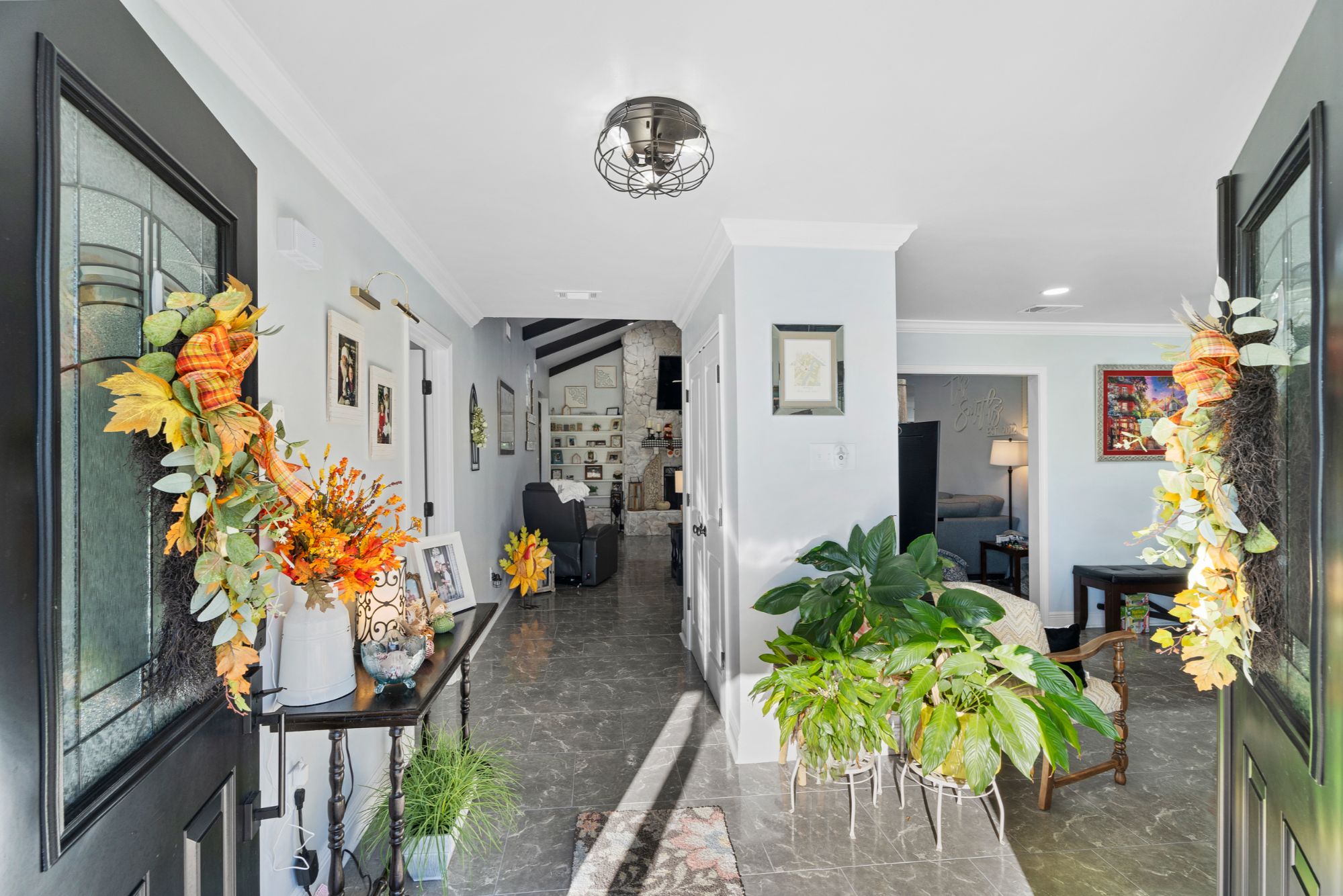 View from the entranceway at 408 Avenue A, Belle Chasse, LA, showing the living room with a brick fireplace straight ahead and the formal dining room to the right, with natural light and high-end floors.