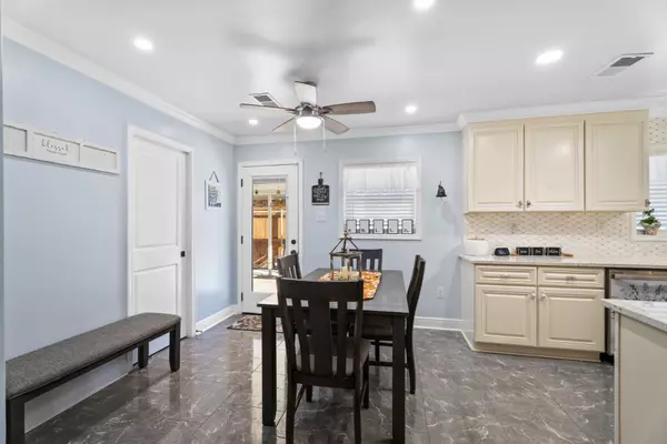 Smaller dining area and kitchen at 408 Avenue A, Belle Chasse, LA, with off-white cabinets, matching appliances, and a door to the covered carport.