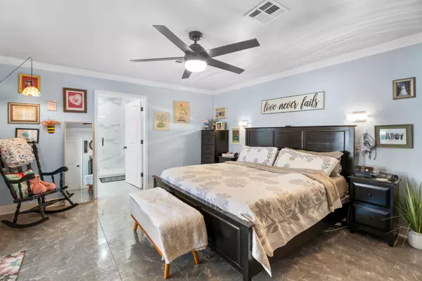 Spacious primary bedroom at 408 Avenue A, Belle Chasse, LA, with a king bed, high-end flooring, and a door to the remodeled bathroom.