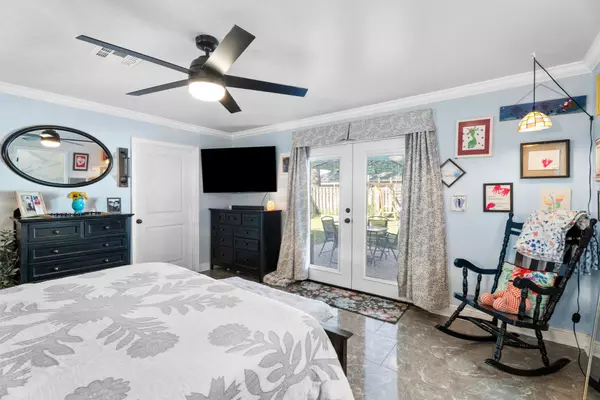 Primary bedroom at 408 Avenue A, Belle Chasse, LA, with double doors to the backyard, a closet door, and natural light highlighting the room’s spacious design.