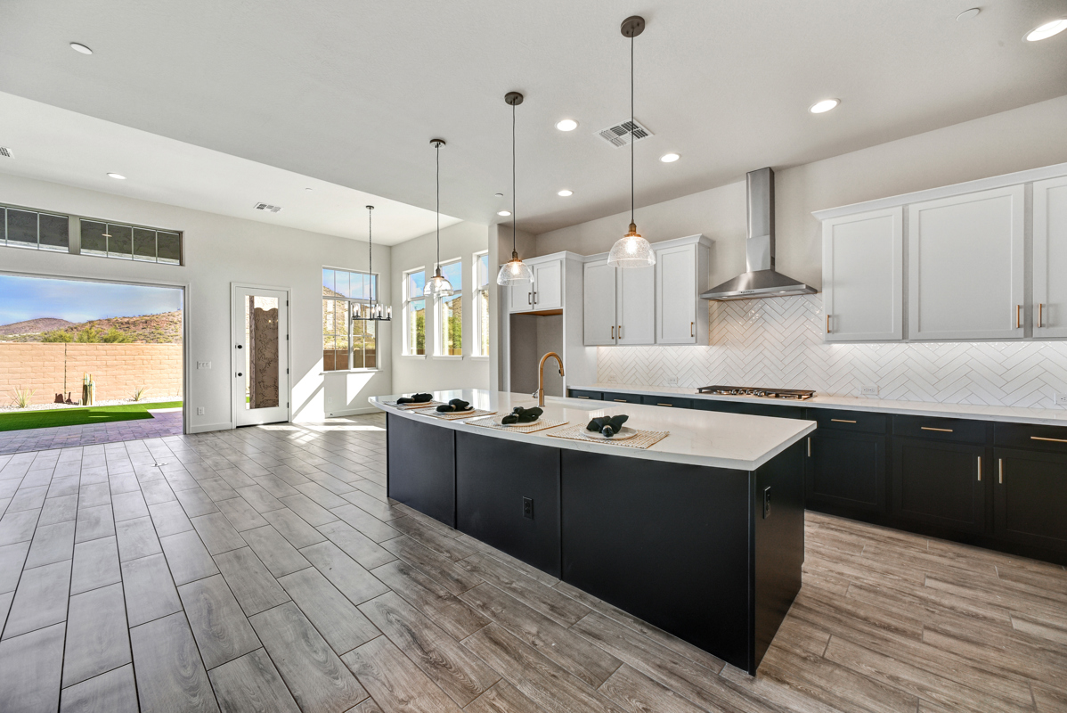 Beautiful new construction home in Peoria, Arizona, showcasing a modern exterior design with energy-efficient windows, a well-manicured yard, and a spacious layout. The home features a stunning gourmet kitchen with an oversized quartz island, upgraded stainless GE appliances, and a designer herringbone tile backsplash, perfect for hosting and family gatherings. Located in the sought-after Northpointe Ascent community, this property blends luxury, style, and functionality for contemporary living.