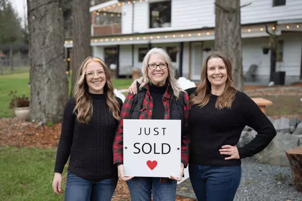 Trusted female realtors on Vancouver Island holding "Just Sold" sign with their client