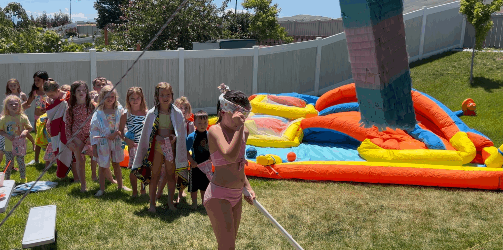 Quincy excitedly hitting her DIY piñata at her 7th birthday party, a colorful handmade creation made from cardboard and party streamers, showcasing a fun and memorable family activity.