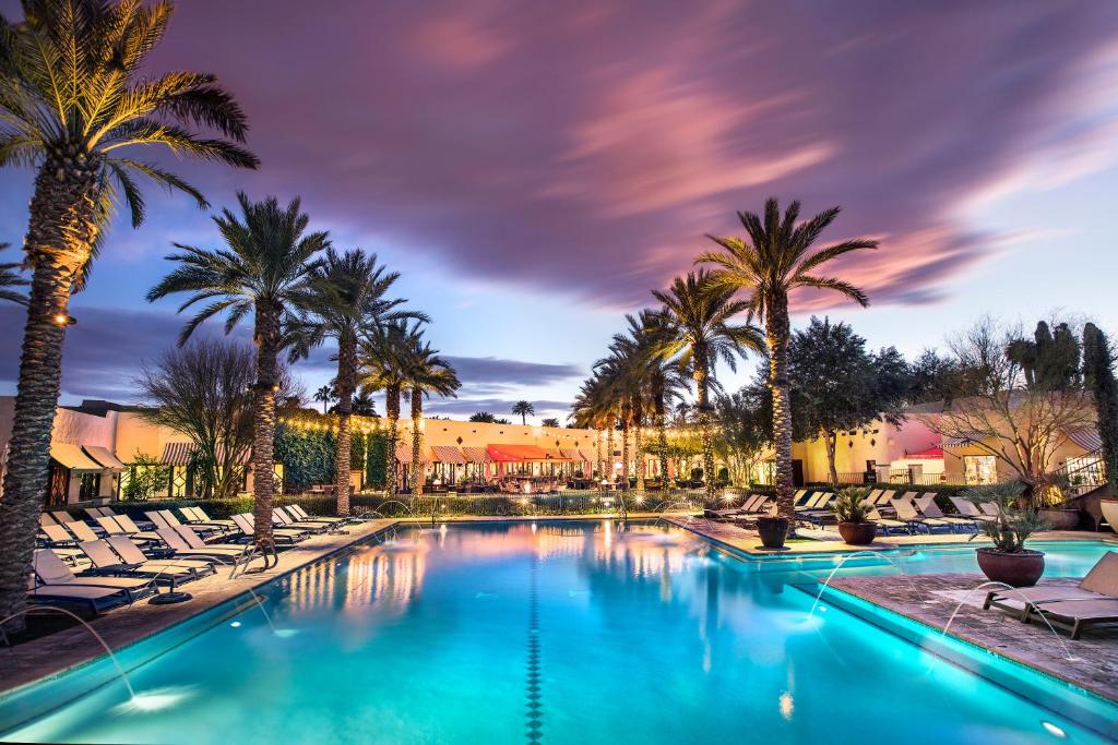 Stunning resort-style pool at the Wigwam Resort in Litchfield Park, AZ, surrounded by palm trees and illuminated at dusk, offering a luxurious and serene atmosphere. The Wigwam community is renowned for its high-end amenities, including pools, golf courses, and dining, making it a premier destination for relaxation and leisure.