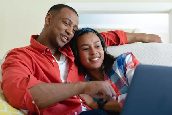 smiling-young-african-american-couple-watching-lap-2022-01-31-18-39-05-utc