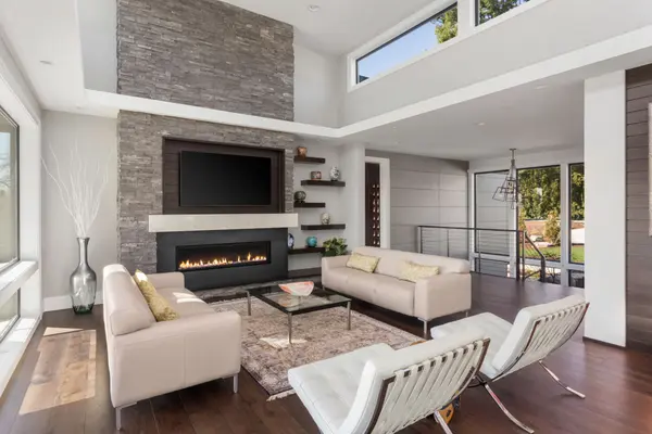 Beautiful living room in new modern luxury home. Features vaulted ceilings, fireplace with roaring fire, clerestory windows, and hardwood floors