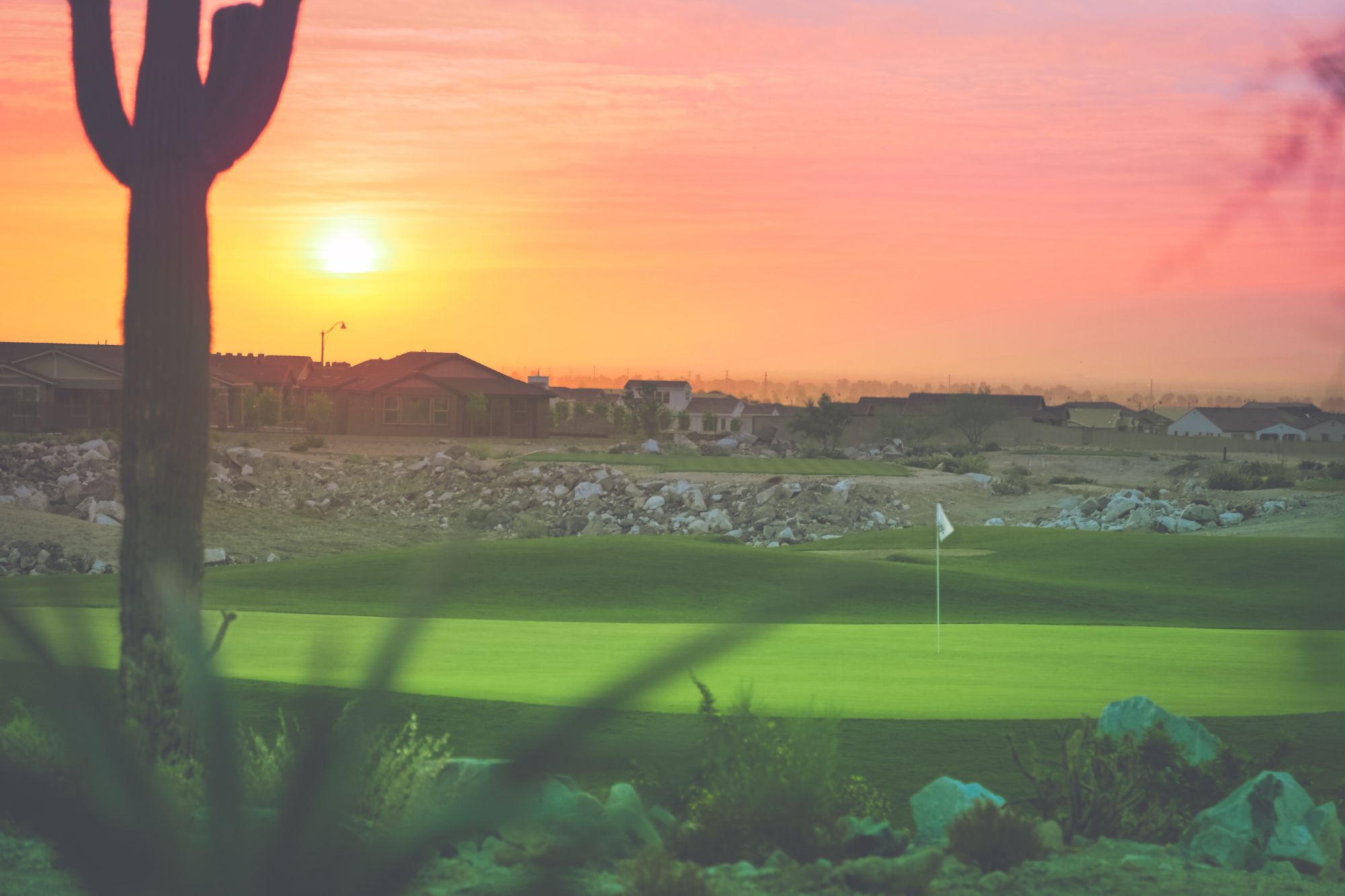 A picturesque sunset view over Verrado Golf Course in Buckeye, Arizona, featuring vibrant desert landscape, homes in the background, and a beautifully maintained green. Buckeye, recognized as the No. 1 city for homeownership in the U.S. in 2024, offers serene living with access to premier amenities like Verrado's championship golf course, making it an ideal location for homeowners and golf enthusiasts alike.