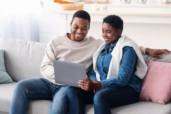 african-american-couple-sitting-on-couch-using-la-2022-12-16-08-47-35-utc