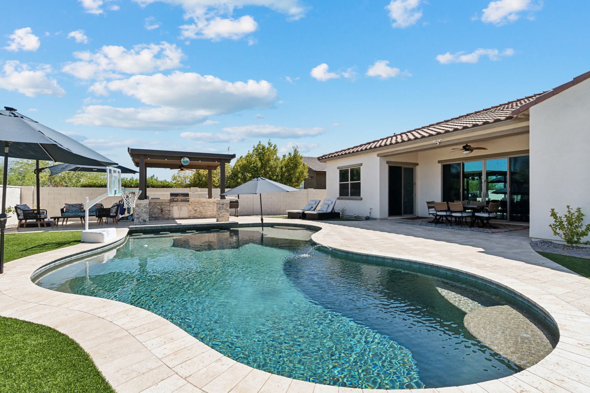 Private backyard oasis with a sparkling pool and swim-up bar, offering stunning desert and mountain views in Verrado, AZ