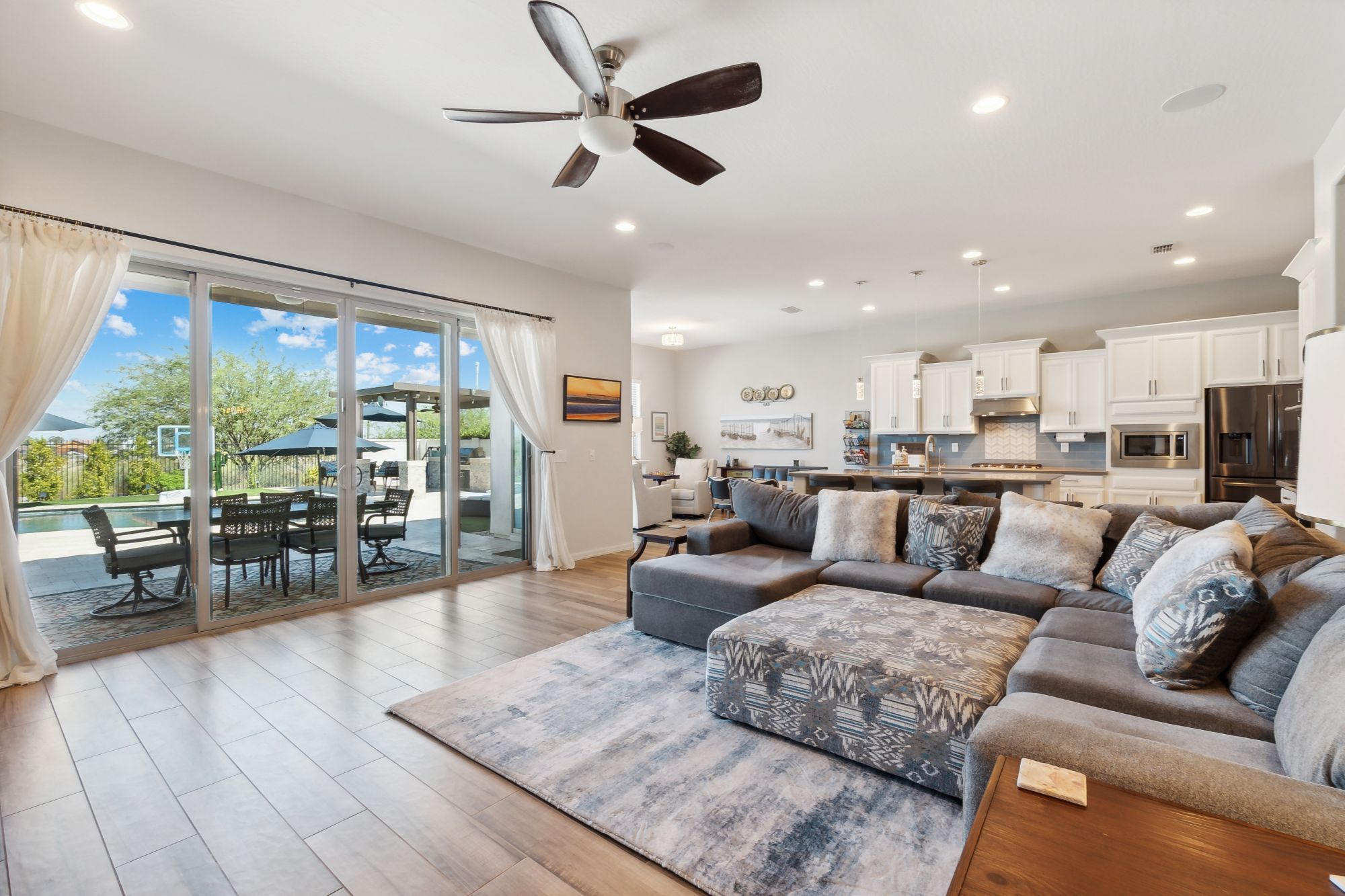 Spacious living room with wood-look tile floors, large windows, and smart home features in a luxury Verrado home.