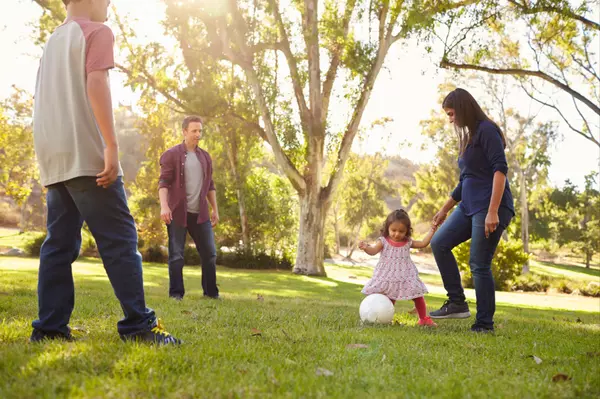 young-mixed-race-family-playing-with-ball-in-a-par-2023-11-27-05-23-49-utc