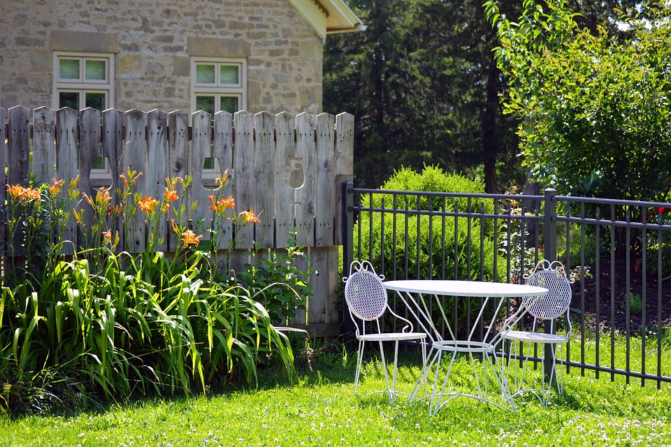 white outdoor table and chairs beside small garden