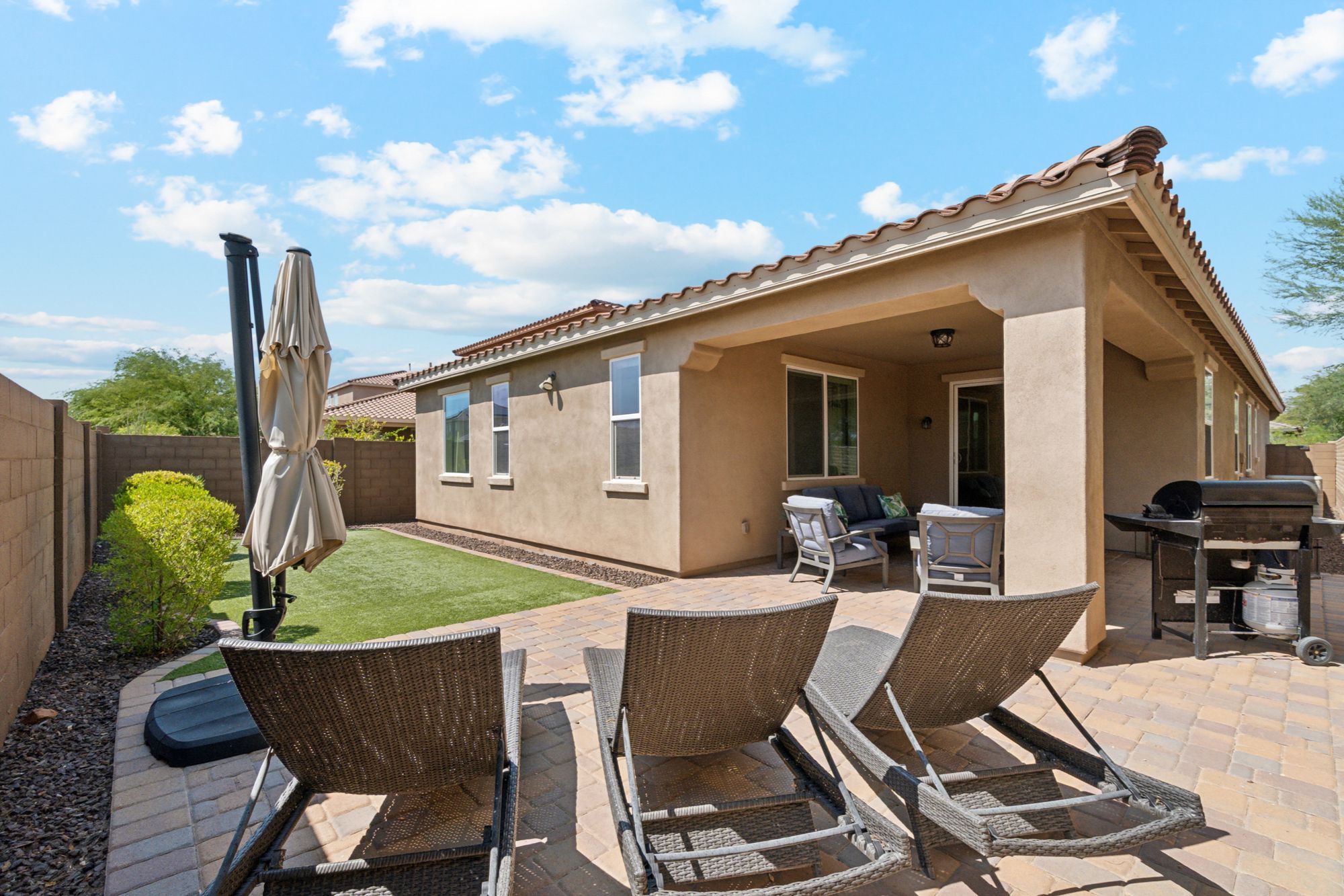 Beautiful backyard of a home in Vistancia, Peoria, AZ, featuring a low-maintenance space with pavers and turf, perfect for relaxation and outdoor enjoyment.