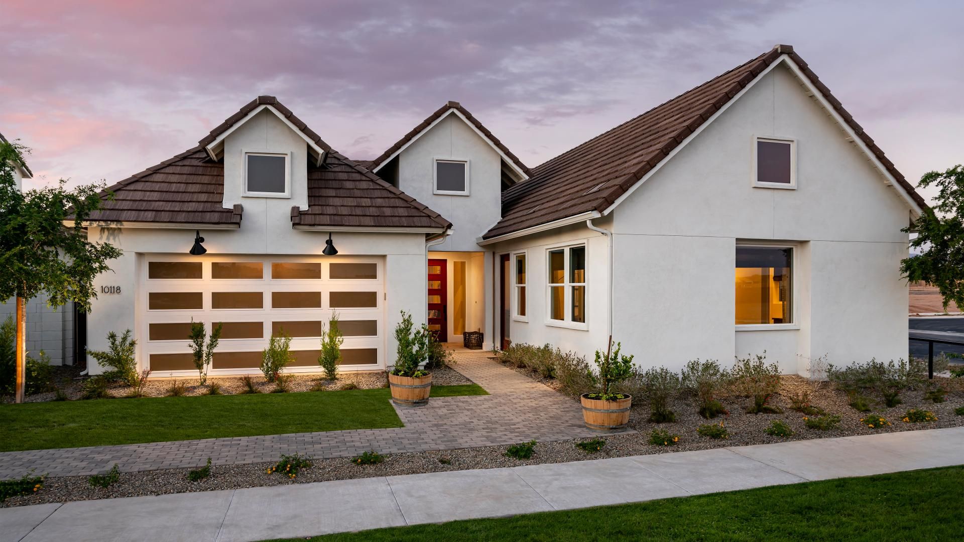 Modern model home in San Tan Valley, Arizona, featuring a contemporary design with clean lines, a charming gabled roof, and a well-landscaped front yard. The home's elegant exterior and inviting entryway showcase the blend of modern and traditional architectural elements, making it a desirable option for homebuyers seeking style and functionality in a growing Arizona community.