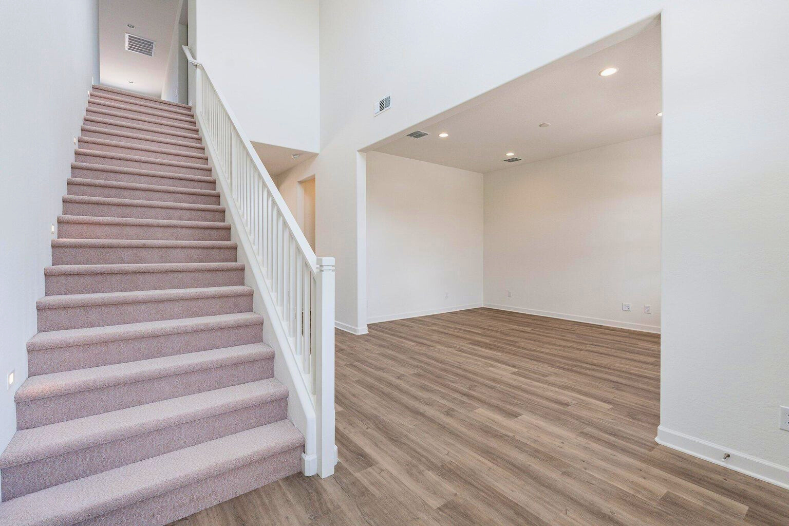 View of the downstairs entry in a luxurious new build home at The Preserve at San Tan, with stairs to the left and a spacious den/office to the right, showcasing modern design and an open, airy layout.