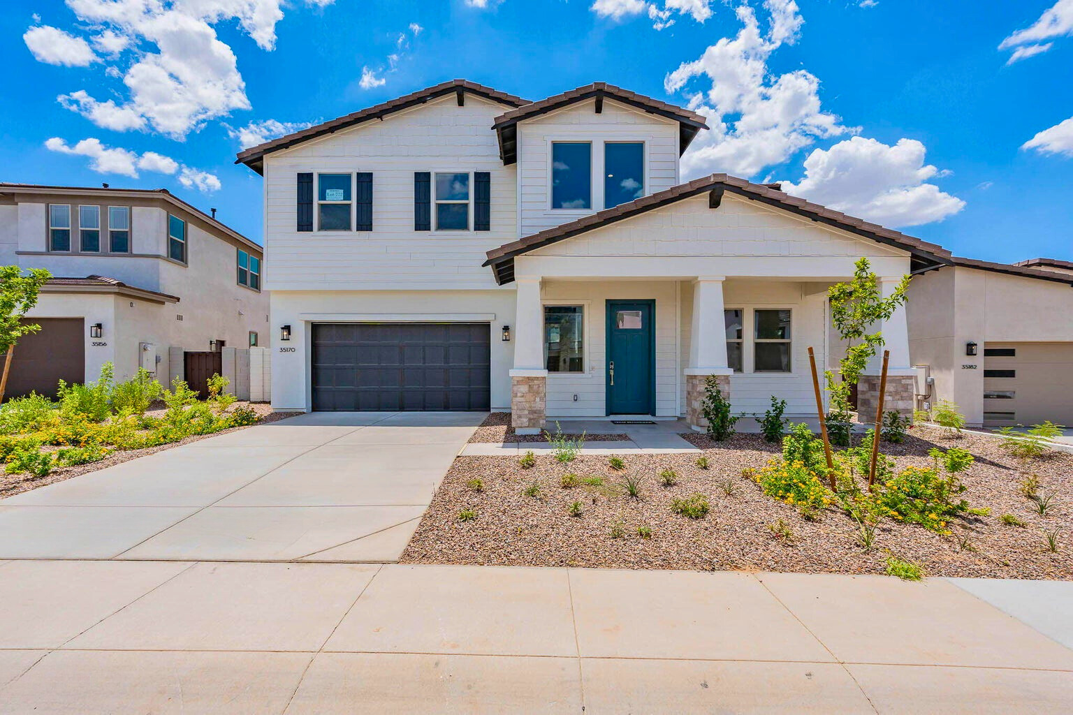 Exterior view of a luxurious new build home in The Preserve at San Tan, San Tan Valley, AZ, featuring modern architecture, a well-manicured front yard, and a spacious driveway leading to a 3-car garage.