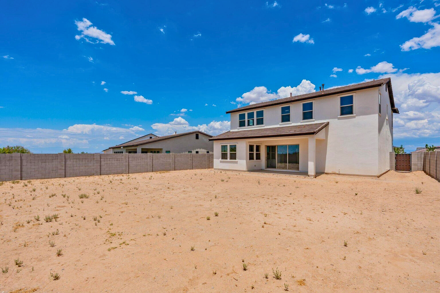 Spacious backyard of a luxury home in The Preserve at San Tan, San Tan Valley, AZ, featuring low-maintenance landscaping, a covered patio, and stunning mountain views.