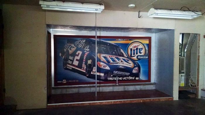 Photo of bizarre real estate photo dancing pole with a nascar poster on wall