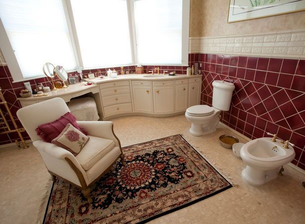 A carpeted bathroom with a vanity, toilet, and bidet arranged like a living room setup, creating an unusual design.