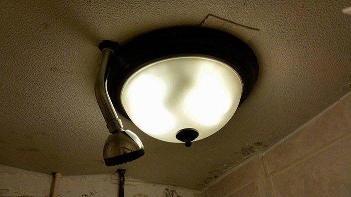 A ceiling light installed next to a shower head, showcasing an odd and potentially unsafe bathroom design.