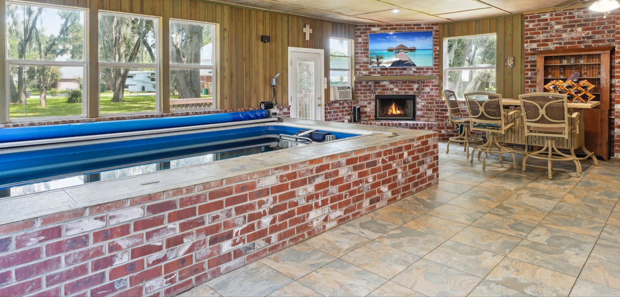 Sunroom with an indoor pool, air conditioning, bar, tv, and fireplace. Perfect spot for entertaining year round. 
