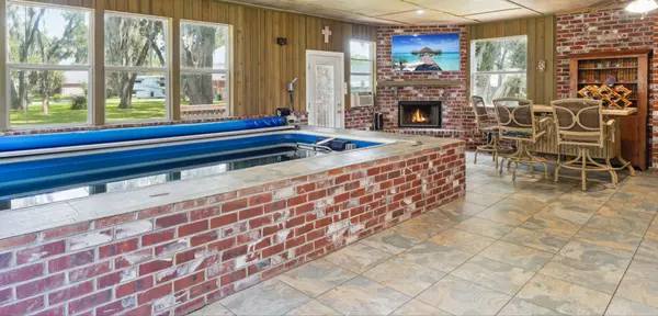 Sunroom with an indoor pool, air conditioning, bar, tv, and fireplace. Perfect spot for entertaining year round.