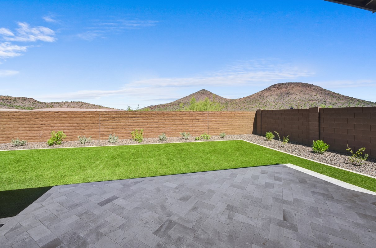 Backyard featuring low-maintenance artificial turf and elegant travertine tile, with a stunning view of nearby mountains in the background.