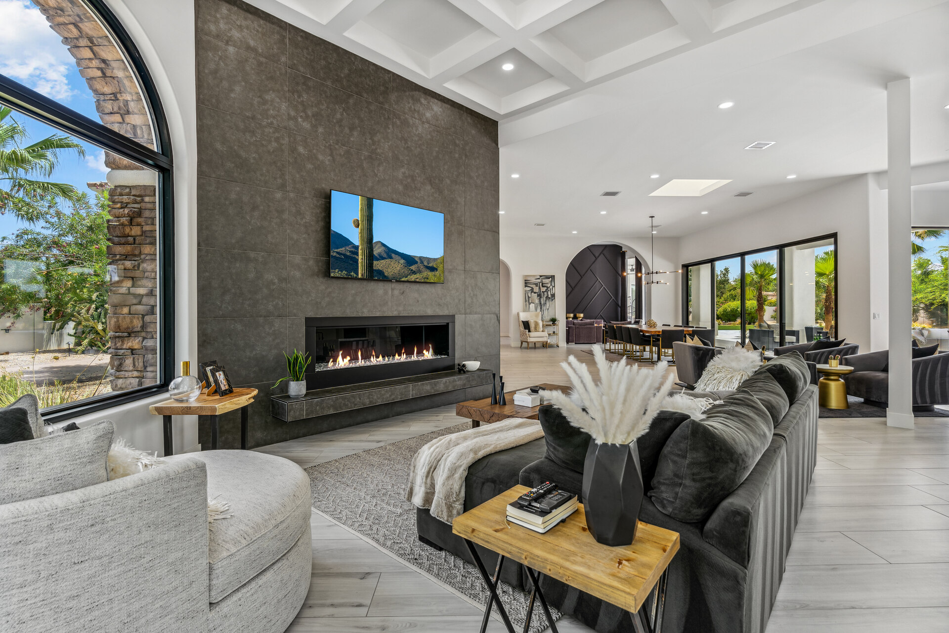 A stunning modern living room with high ceilings, an elegant coffered design, a contemporary fireplace, and expansive windows that connect indoor and outdoor spaces, emphasizing natural light and luxurious functionality, as highlighted in the 2025 home design trends.