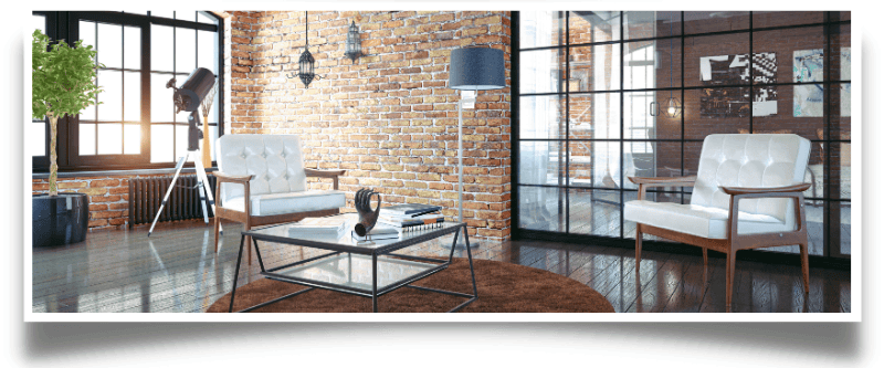 Modern loft living room with exposed brick, glass coffee table, and mid-century armchairs.