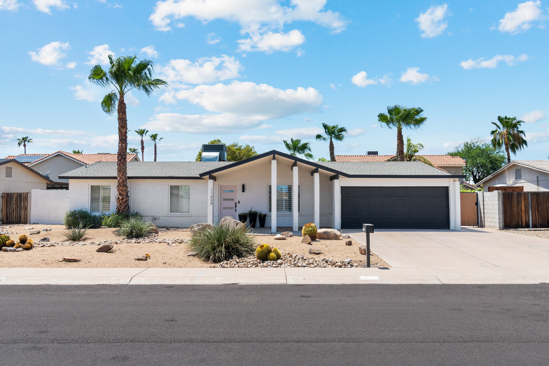Modern single-story home in Phoenix, Arizona, perfect for first-time home buyers or real estate investors. Featuring desert landscaping, palm trees, a black garage door, and a stylish white exterior with a covered front porch. A great example of a primary home with rental potential, offering strong appreciation upside and an opportunity to build wealth through real estate. Located in a high-demand market with growth potential, making it an ideal choice for buyers looking to start or expand their real estate portfolio.