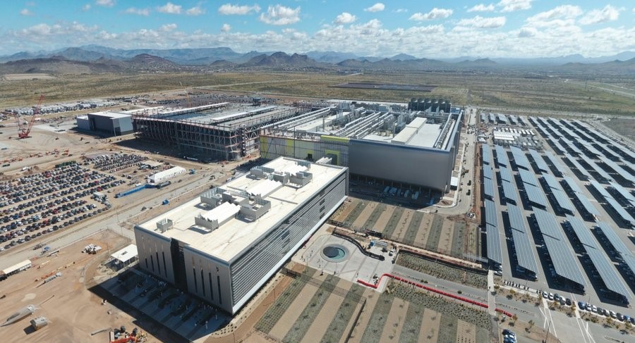 Aerial view of the Taiwan Semiconductor Manufacturing Company (TSMC) Phoenix plant under construction in Arizona, featuring large industrial buildings, expansive infrastructure, and active construction sites. As part of TSMC's record-breaking $165 billion investment in U.S. semiconductor manufacturing, this advanced fabrication facility will bolster domestic chip production, create thousands of high-tech jobs, and strengthen America's supply chain resilience in the semiconductor industry.