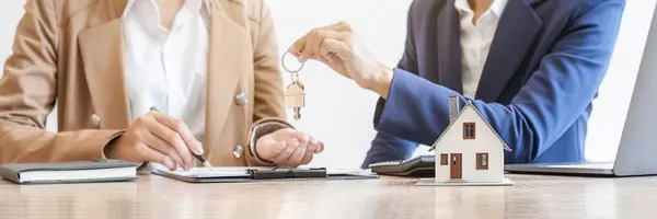 Real estate agent holding a key and asking costumer for contract to buy, get insurance or loan real estate or property