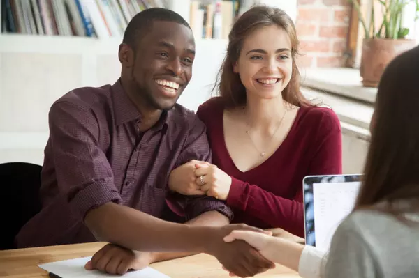 Smiling multiracial couple customers shaking hands with mortgage broker or financial advisor